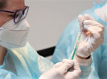 Ärztin mit Schutzausrüstung bereitet Injektion vor